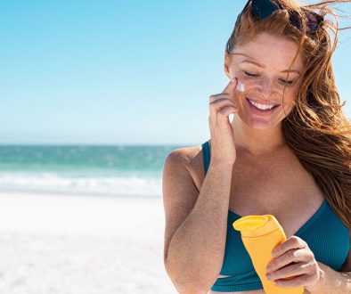 woman holding suncreen on beach