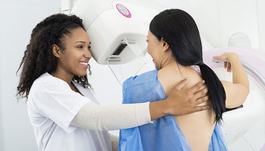 Women receiving breast mammogram from a nurse.