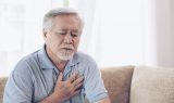 Senior Asian male holding chest because of heart burn.