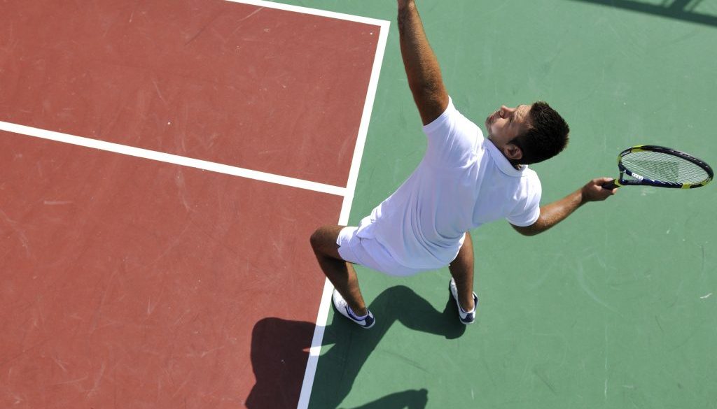 Man serving a tennis ball common shoulder injuries