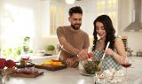Lovely Young Couple Cooking Salad Together In Kitchen