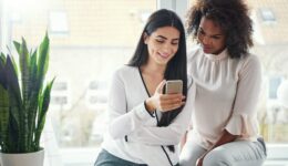 Two women looking at a phone together find a new obgyn
