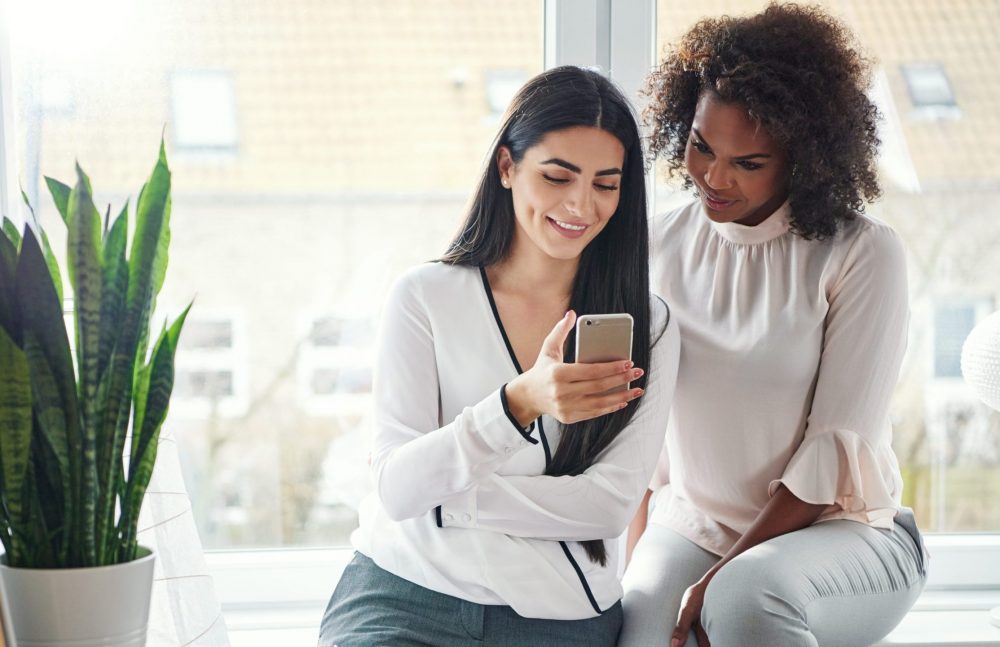 Two women looking at a phone together find a new obgyn