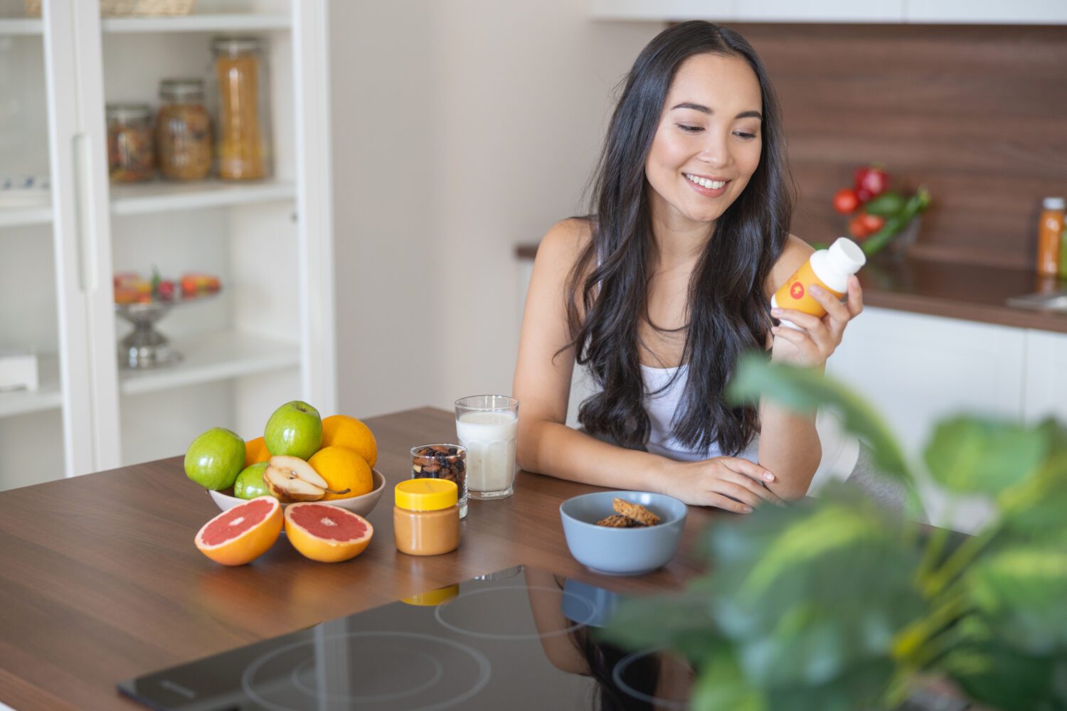 Young woman taking a nutritional supplement at breakfast