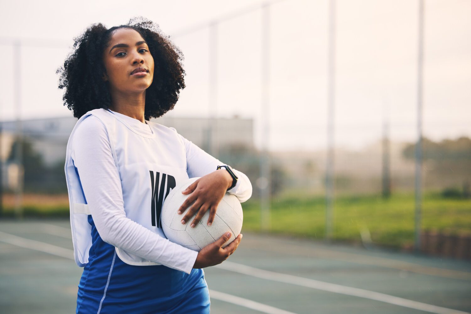 Sports, netball and portrait of female with a ball after match, exercise or training on the court. Confidence, fitness and serious black woman athlete standing on field for game, workout or practice.