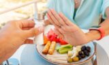 Woman in a restaurant refuses the offered salt and pepper shaker with a gesture of her hand. Diet for gout and high cardiovascular blood pressure