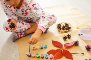 little girl is painting the color on pine cones