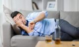 alcoholic lying on sofa and looking at wristwatch