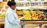 African american woman checking her grocery list while in the store healthy grocery shopping