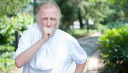 Elderly man coughing outdoors dealing with COPD Flare-ups