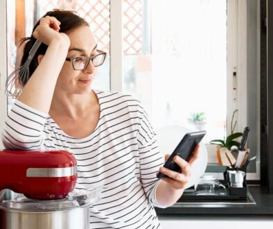 A woman resting her arm on a stand mixer while reading on her phone Gluten Free Diet Tips